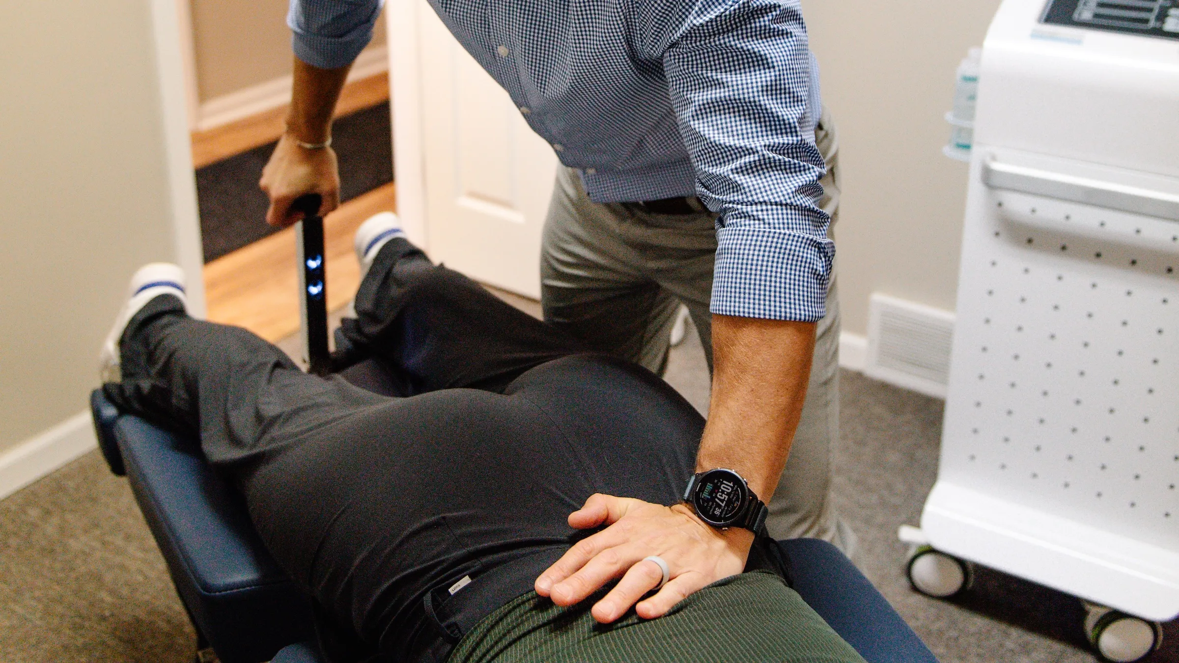 Dr. RJ Burr working the lever of a Cox flexion-distraction table with his other hand on a patient's lower back, at REACH Rehab + Chiropractic, Plymouth MI