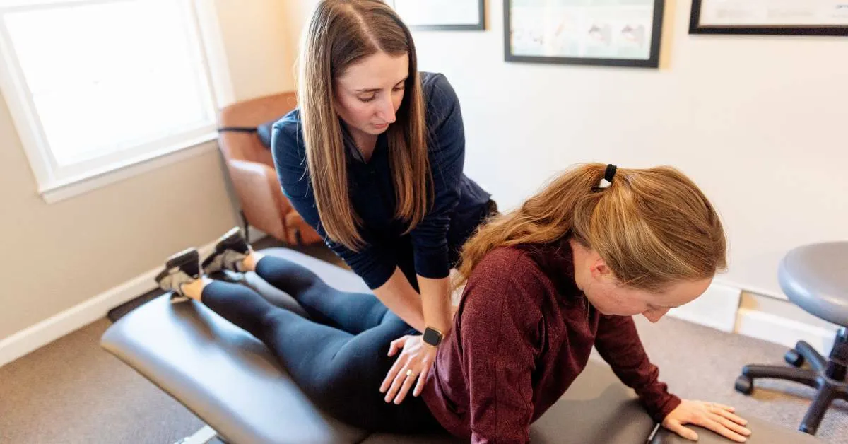 Dr. Sheridan Kent assessing a patient's low back and pelvis at REACH Rehab + Chiropractic
